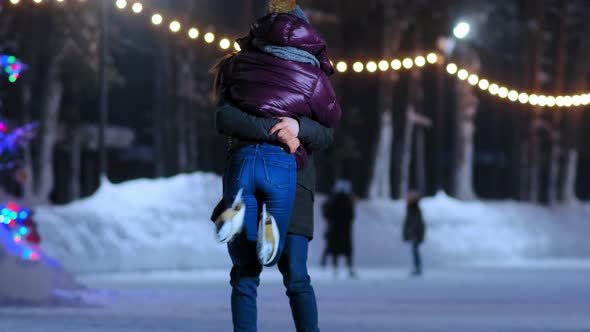 Boyfriend Lifts Up Girl in Short Jacket Having Fun on Rink alt