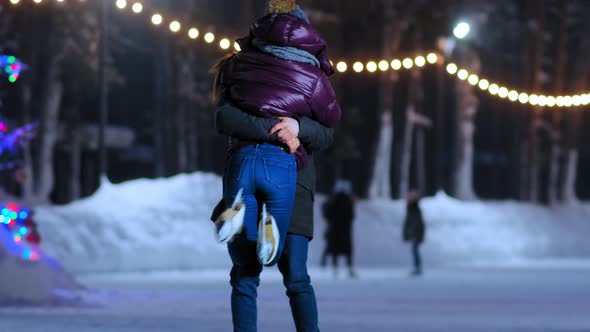 Boyfriend Lifts Up Girl in Short Jacket Having Fun on Rink