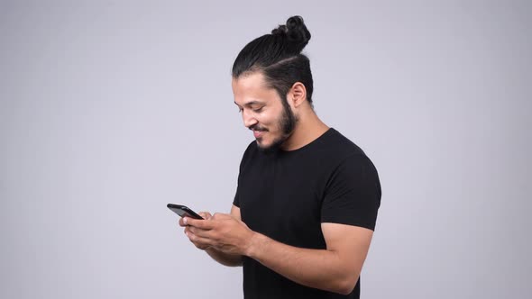 Happy Indian man chatting with someone using smart phone alt