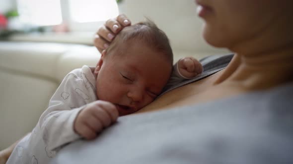 Close Up of Newborn Baby Dreaming on Mothers Chest in Hospital Delivery Room alt