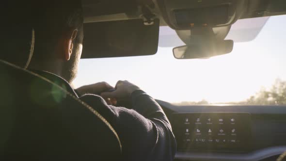 A Middleaged Handsome Caucasian Man Drives a Car on a Road As the Sun Shines Through the Windshield