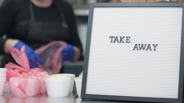 Take Away Announcement Closeup with Blurred Woman Packing Food Containers with Donations for alt