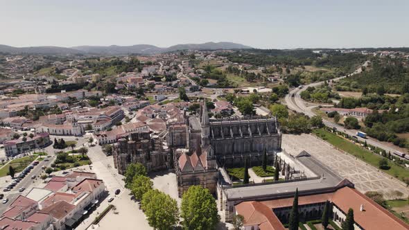 Batalha city rooftops and majestic historical monastery, aerial drone orbit view alt