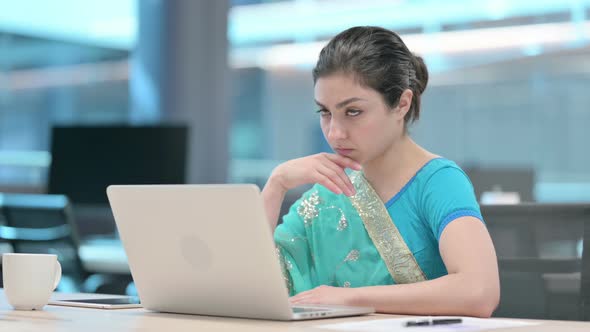 Young Indian Woman Thinking while using Laptop alt