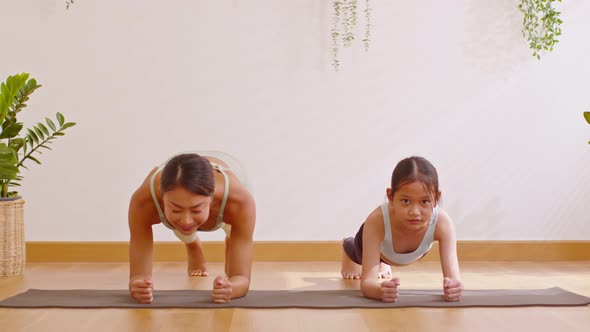 Healthy couple mom and little girl doing yoga plank pose on yoga mat at home.Female mother and daugh alt