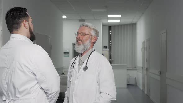 Senior Doctor Smiling Cheerfully Talking To His Colleague