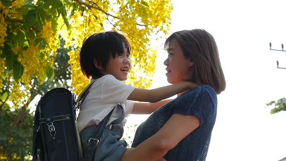 Asian Mother Holding Her Son While Walking In The Park , Back To School Concept alt
