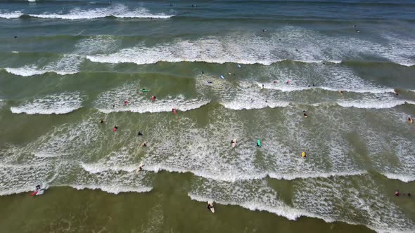 Birds eye drone shot of Muizenberg beach, Cape Town - drone is descending over surfers trying to cat alt