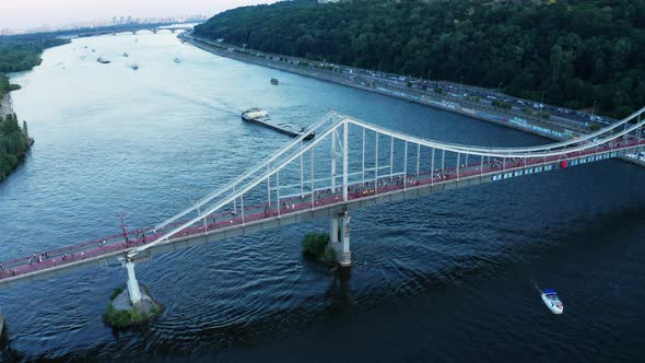 View of Pedestrian Bridge with People Walking Across the Dnipo River in Kiev alt