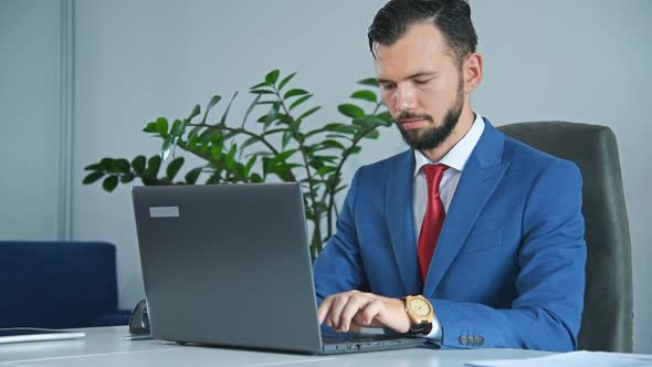 Businessman Sitting In Office And Typing On Laptop