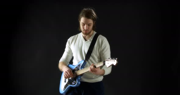 Creative Musician in a Gray Jumper on a Black Background Plays Electric Guitar