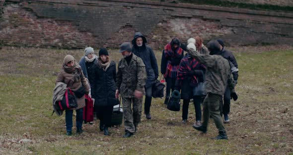 Military Soldiers Walking Ahead Of Refugee Group alt