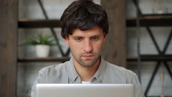 Happy Winner. Young Excited Man Using Laptop Computer While Sitting on Sofa. alt
