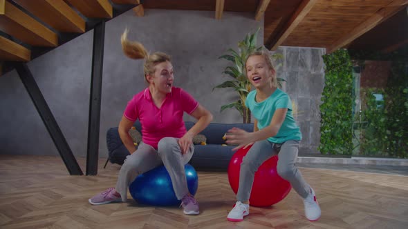 Happy Mom and Child Frolicking on Fitness Balls alt