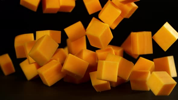 Super Slow Motion Shot of Cheddar Cheese Cubes Falling on Black Background at 1000 Fps. alt