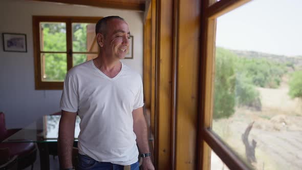 Handsome Man Smiling Looking Out the Window at Winery Plantation Standing in Restaurant Indoors alt