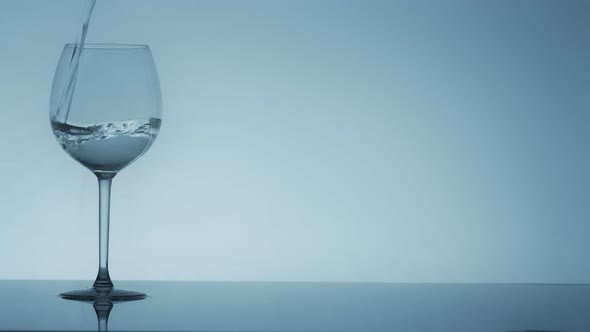 Studio Shoot of Water Pouring Into Transparent Glass on White Background alt