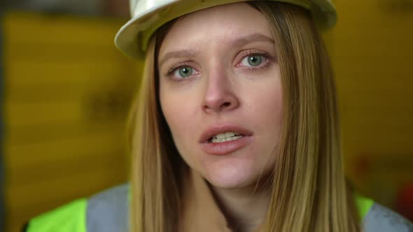 Headshot Annoyed Female Employee in Hard Hat Looking at Camera with Unsatisfied Facial Expression alt