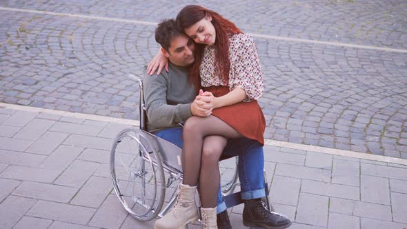 disabled person in love - man with paraplegia holding hands with girlfriend alt