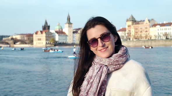 Medium Closeup Adorable Young Smiling Woman Posing on Embankment of Typical European City at Sunset alt