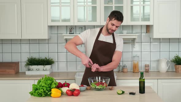 Male Chef Adding Spices to Vegan Salad While Standing in Kitchen at Home alt