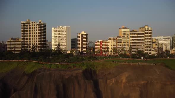 AERIAL - Cliffs, coastline in luxurious Miraflores, Lima, Peru, wide rising shot alt