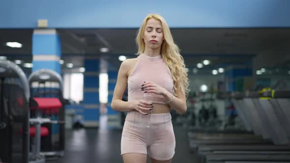 Portrait of Blond Confident Sportswoman Walking to Camera Drinking Refreshing Water alt