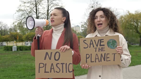 Two Women are Standing with Posters SAVE THE PLANET and NO PLASTIC alt