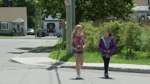 Young girls walking to school carrying a football alt