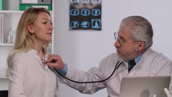 Family Medicine Doctor Examines a Woman Patient with a Stethoscope alt