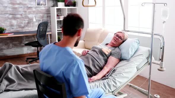 Male Nurse in Nursing Home Talking with Old Woman alt