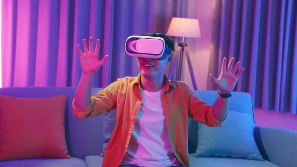 Young Asian Man Explores Virtual Reality At Living Room, Cyan And Magenta Colours alt