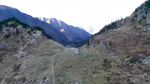 Hikers at Lac d'Espingo ridge in Haute-Garonne, Pyrénées mountains, France, Aerial dolly out reveal alt