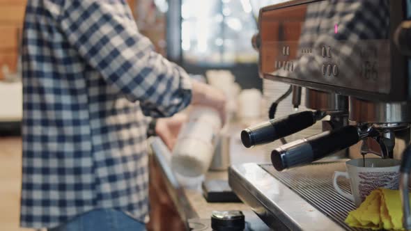 Male barista works at counter in cafe