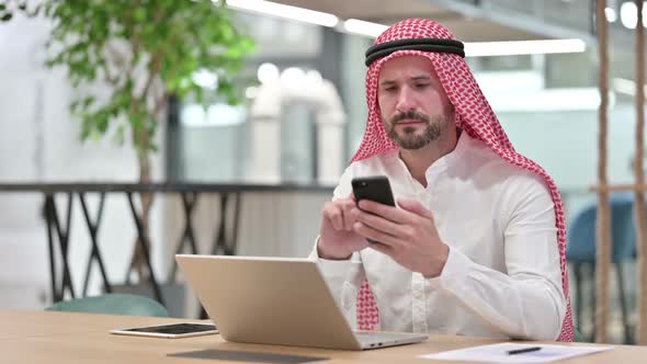 Professional Arab Businessman Using Smartphone and Laptop alt