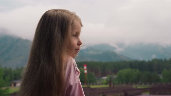 Amazed Little Girl Enjoys View of Misty Mountains at Resort alt