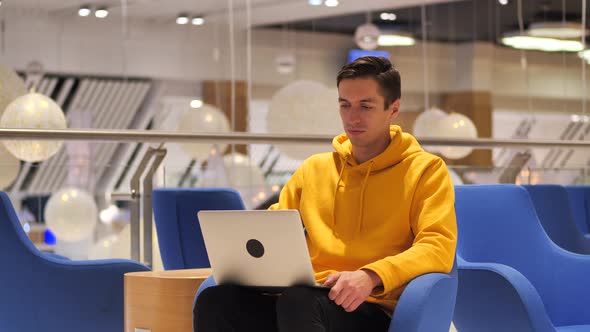 Young Confident Busy Man Working on a Laptop While Sitting in a Cafe alt