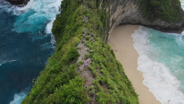 Man hiking down sharp cliff with idyllic beach in background, Aerial, Bali alt