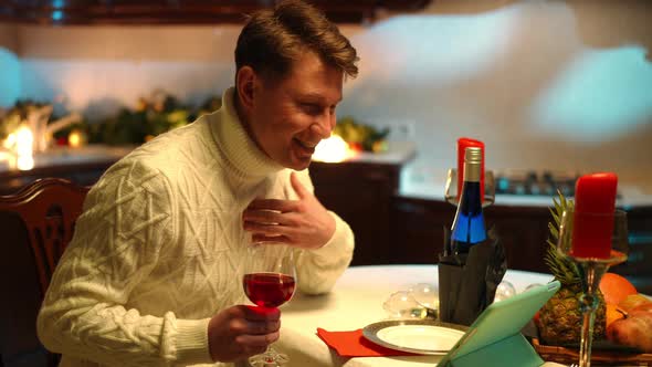 Side View Happy Man Waving at Tablet Video Chat Talking Sitting at Table with Red Wine alt