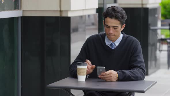 Young businessman using cell phone at outdoor cafe