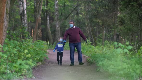 A Father and Son in Medical Masks Walk in the Park in the Spring. The Concept of Protection FROM