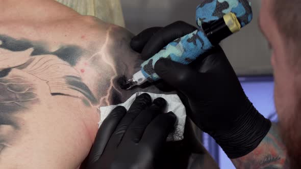 Cropped Shot of a Professional Tattooist Working at His Studio alt