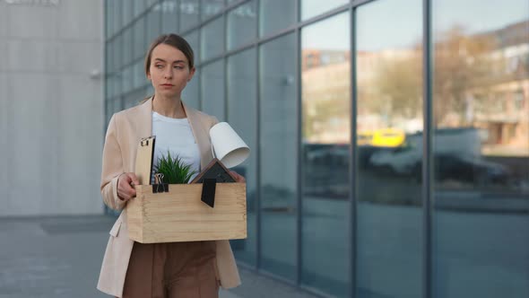 Woman Walking Near Modern Business Center with Box of Items alt