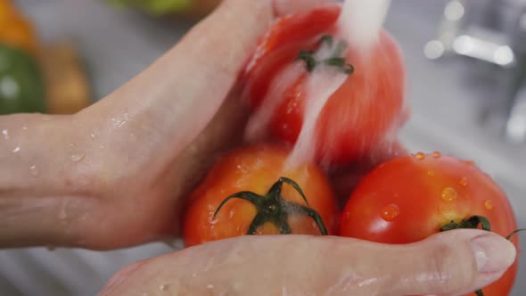 Close up of Woman Hand Washing a Fresh Red Organic Tomato