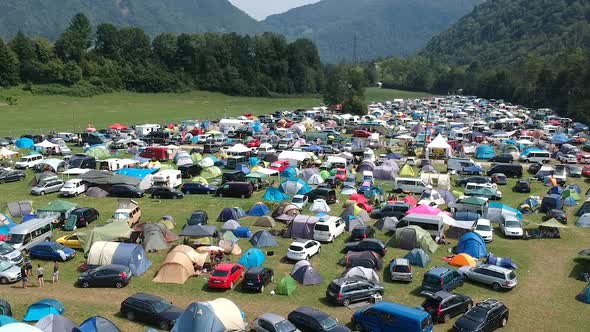 Aerial drone shot of a camping ground at a music festival in a green and lush mountainous area. alt