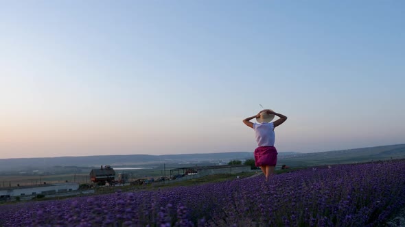 Woman in a Short Purple Dress and a Hat Stands on a Lavender Field alt