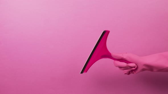 A Hand in a Pink Rubber Glove with a Plastic Scraper for Handwashing Windows