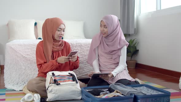 Young beautiful muslim woman and girlfriend preparing item for travel
