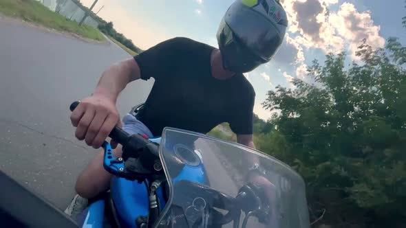 A Young Man Rides a Motorcycle Outside the City