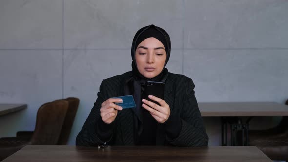 Young Muslim Woman in Hijab Shopping Online on Mobile Phone with Credit Card
